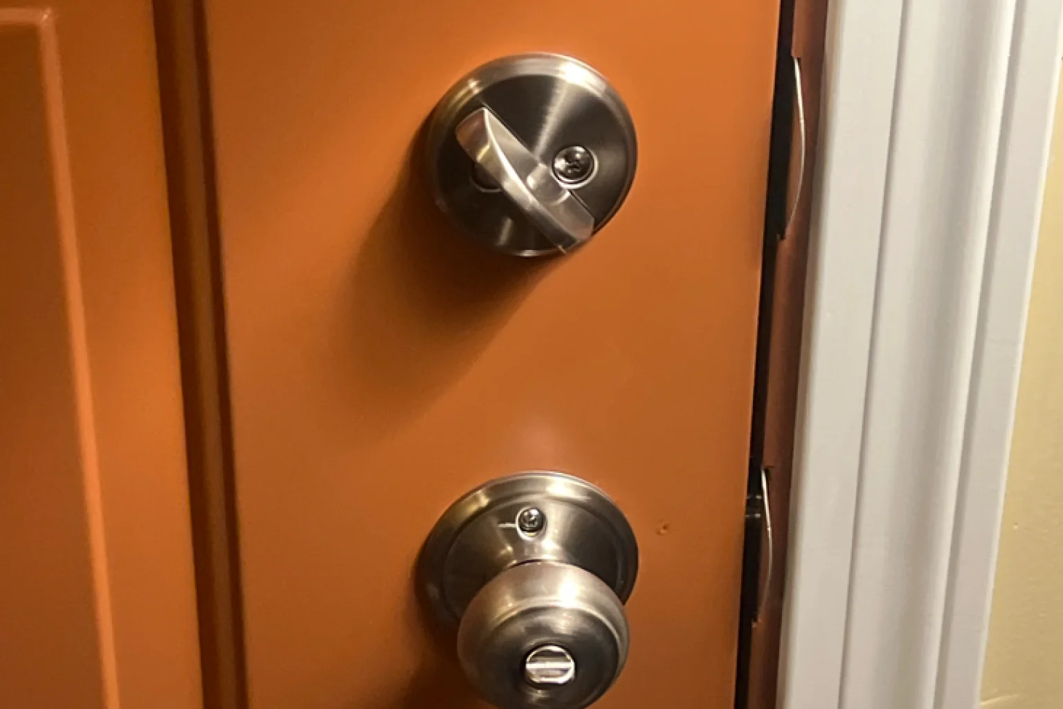 Stainless steel deadbolt and door knob installation on orange door